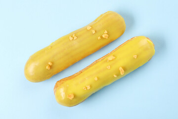 Delicious eclairs covered with glaze on light blue background, top view