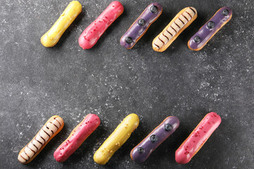 Different tasty glazed eclairs on dark textured table, flat lay. Space for text