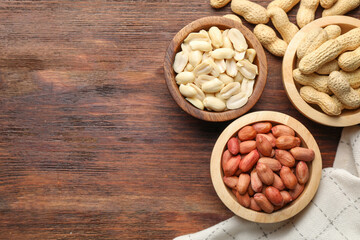 Fresh peanuts in bowls on wooden table, top view. Space for text