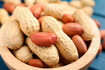 Fresh unpeeled peanuts in bowl on table, closeup