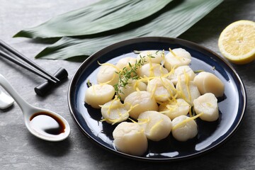 Raw scallops with thyme and lemon zest on grey marble table, closeup
