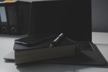 Office workplace with text space, White wooden table with office supplies tablet, desktop computer and book, top view, over light