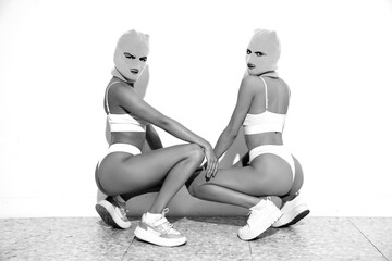Two beautiful sexy women in underwear. Models wearing bandit balaclava mask. Hot seductive female...