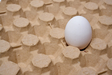 Crack open white organic egg in an egg box. Corrugated egg box.
