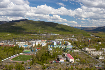 Ust-Omchug, Magadan region, Russia. View from above on the northern village, located in a picturesque valley among the mountains. Beautiful summer landscape. Travel to Siberia and the Russian Far East