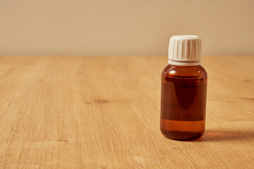 Red, empty glass medicine bottle on a wooden table.