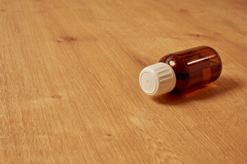 Red, empty glass medicine bottle on a wooden table.