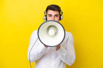 Telemarketer caucasian man working with a headset isolated on yellow background shouting through a megaphone