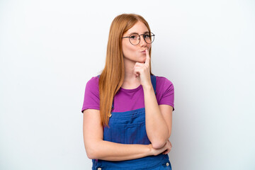 Young redhead woman isolated on white background having doubts while looking up