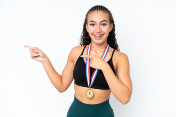 Young sport woman with medals isolated on white background surprised and pointing side