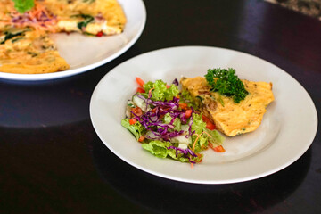 Omelet with vegetable salad on a white plate