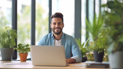 Man sitting at a desk with a laptop in front of him, smiling