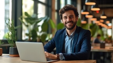 A man in a suit works on his laptop at a desk in a modern office