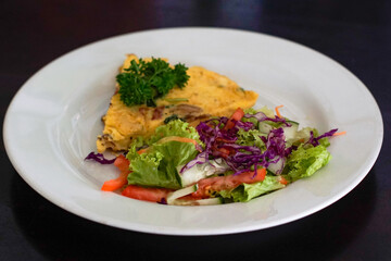 Omelet with vegetable salad on a white plate