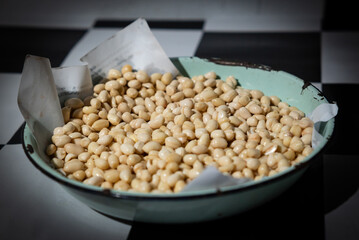 Fresh, skinned raw peanuts are placed in a green enamel bowl.