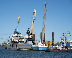 Fototapeta premium three coloured harbour cranes and several sea boats