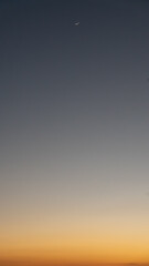 オレンジに染まる夕景と三日月