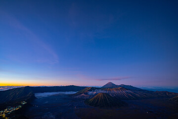 Bright morning colors on the horizon..The sun shines brightly over the sea of ​​mist at Bromo Volcano, Indonesia. At the top of the steep mountain you can see a volcanic crater and a sea of ​​mist.