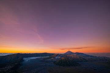 Bright morning colors on the horizon..The sun shines brightly over the sea of ​​mist at Bromo Volcano, Indonesia. At the top of the steep mountain you can see a volcanic crater and a sea of ​​mist.