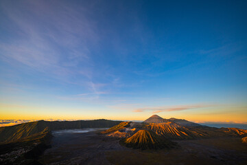 Bright morning colors on the horizon..The sun shines brightly over the sea of ​​mist at Bromo Volcano, Indonesia. At the top of the steep mountain you can see a volcanic crater and a sea of ​​mist.