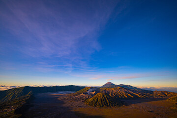 Bright morning colors on the horizon..The sun shines brightly over the sea of ​​mist at Bromo Volcano, Indonesia. At the top of the steep mountain you can see a volcanic crater and a sea of ​​mist.