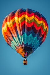 Fototapeta premium A colorful hot air balloon against a clear blue sky, highlighting its vibrant patterns and the adventure of ballooning.