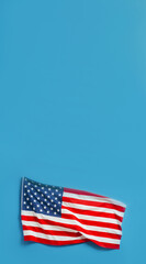 Obraz premium American flag against blue background, US flag is at bottom of frame, vertical banner with copy space for patriotism, national pride, national holidays, political events