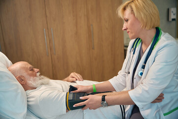 Doctor measuring blood pressure of old patient