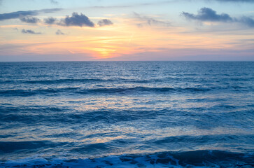Rocky shoreline bathed in the warm glow of sunset providing a scenic view with copy space image 1