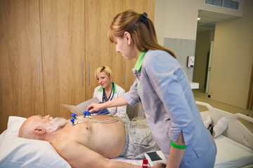 Assistant and a doctor perform a cardiogram for a patient
