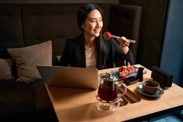 Asian lady having lunch before online video conference