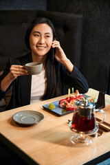 Happy woman enjoying tea and sushi set, celebrating job promotion