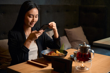 Attractive woman posting photos of restaurant in social networks
