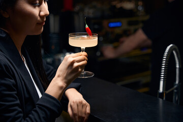 Asian woman holding at originally served white signature cocktail
