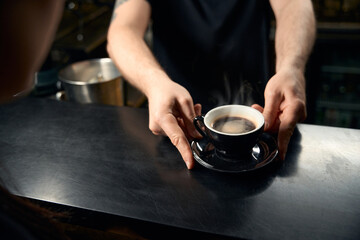 Professional bartender serving the cup of freshly brewed fragrant coffee