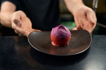 The waiter serving the round dessert in chocolate