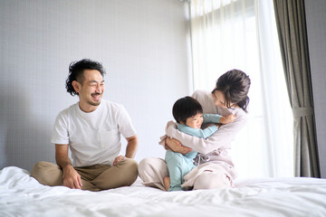 Obraz premium ベッドではしゃぐ3人家族