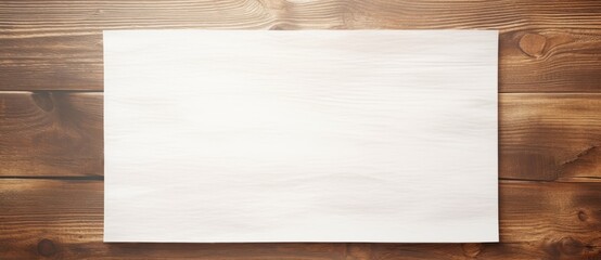 Naklejka premium Blank white sheet of paper lying on top of a wooden table.