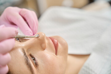 Dermatologist in gloves conducting mechanical comedo extraction on patient