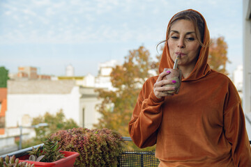 Portrait of Latin Woman at home drinking mate enjoying the tranquility in the balcony
