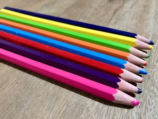 Fototapeta premium Bunch of fun mini colored pencils isolated on wood background. Multicolor group of cute small wooden pencils