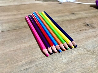 Fototapeta premium Bunch of fun mini colored pencils isolated on wood background. Multicolor group of cute small wooden pencils