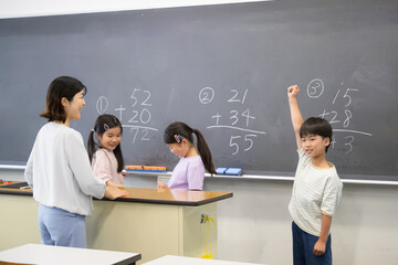 Elementary school boy studying math on the blackboard Well done!