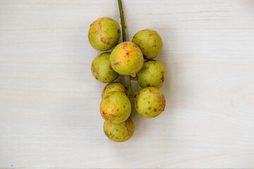 Fresh Rambai (Baccaurea motleyana) fruits isolated on light wooden surface. It is also known Rambi, Lotkon, Lotka, or Bugi. Top view.