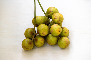 Bunch of Rambai or Rambi fruits isolated on light wooden surface. It's scientefic name is Baccaurea motleyana. Locally In Bangladesh, It is known as Lotkon, Lotka, or Bugi.