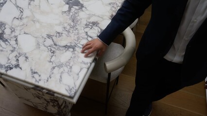 Tabletop made of white marble, a man's hand touches the table.