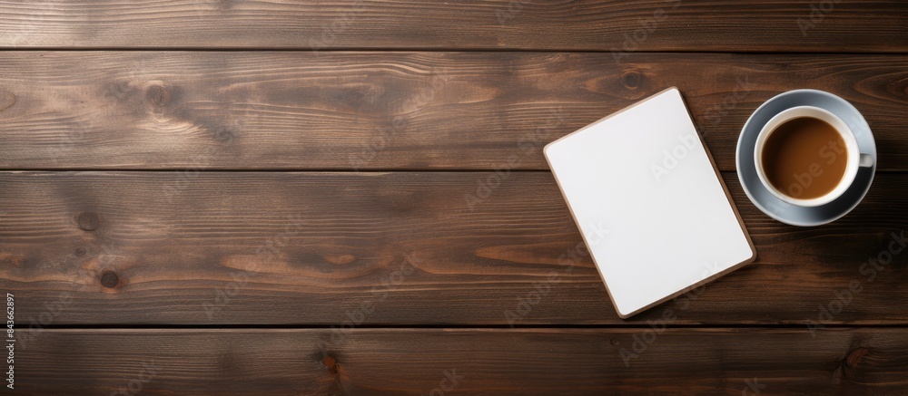 Poster tablet with cup of coffee and notepad on wooden table. copy space available