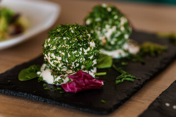 Cheese balls with herbs on a black board on a white background