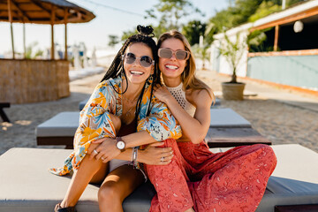 two stylish beautiful women relaxing having fun on beach in summer fashion trend outfit