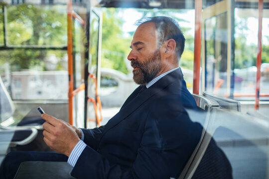 Businessman smiling while using a smartphone on a bus